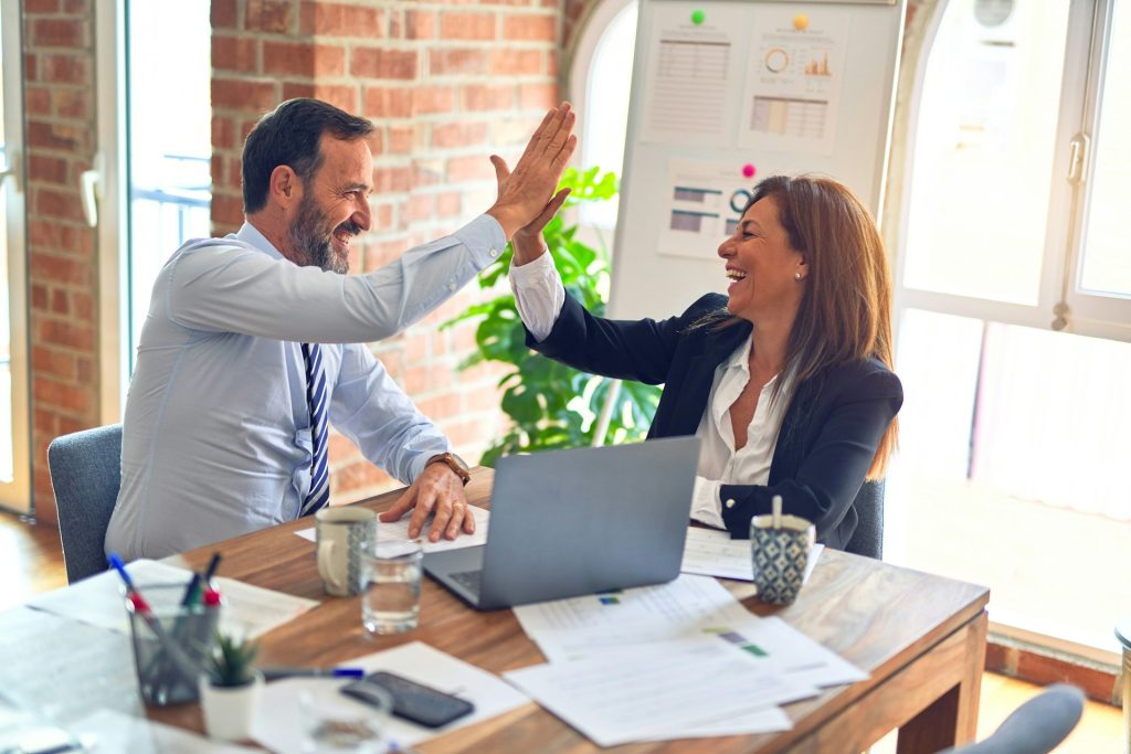 Consultante et client de l’agence marketing BMO Conseil se tapant dans la main devant un ordinateur